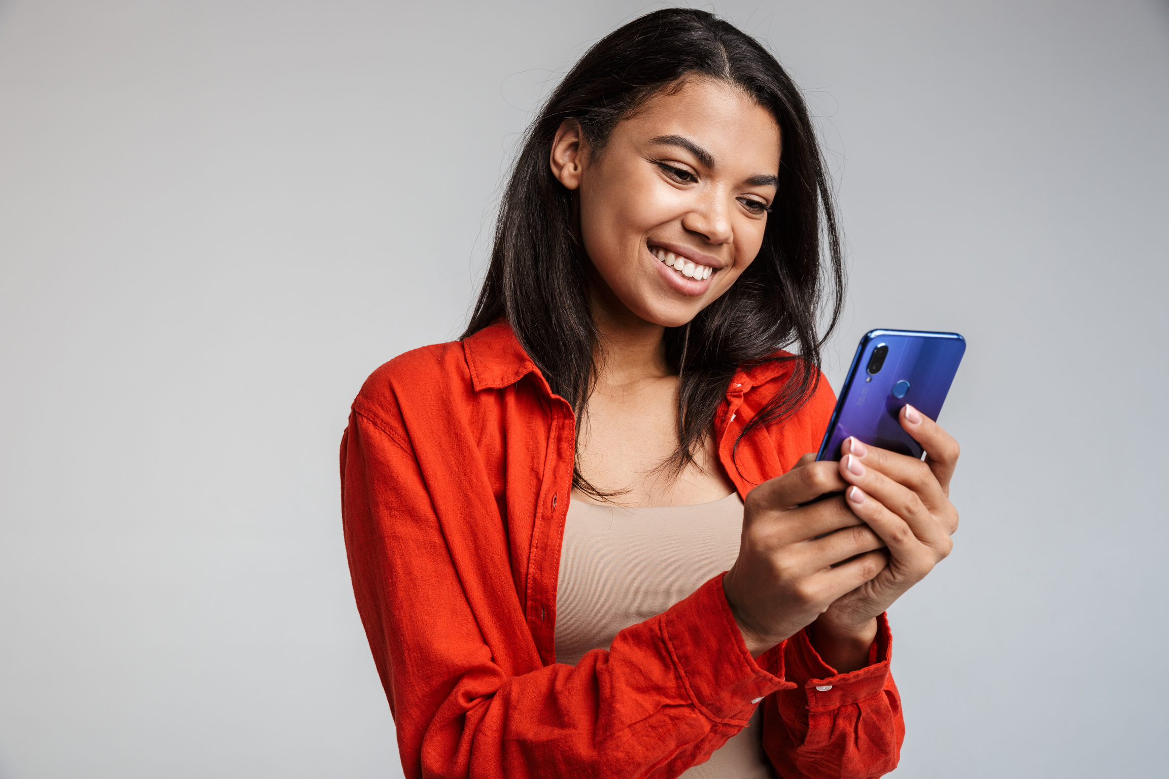 Smiling Young African Woman Texting on Mobile Phone